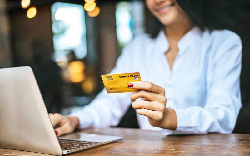 woman sat with a laptop and paid with a credit card in a coffee shop.