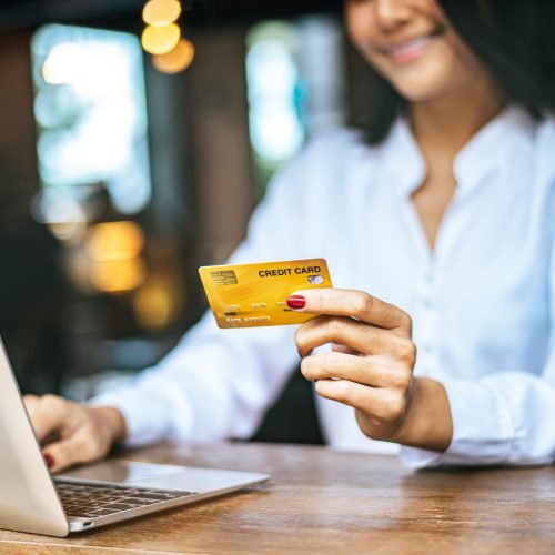 woman sat with a laptop and paid with a credit card in a coffee shop.